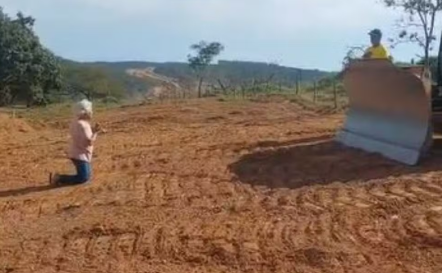 Idosa se ajoelha diante de máquina para tentar barrar obra de duplicação da GO-330